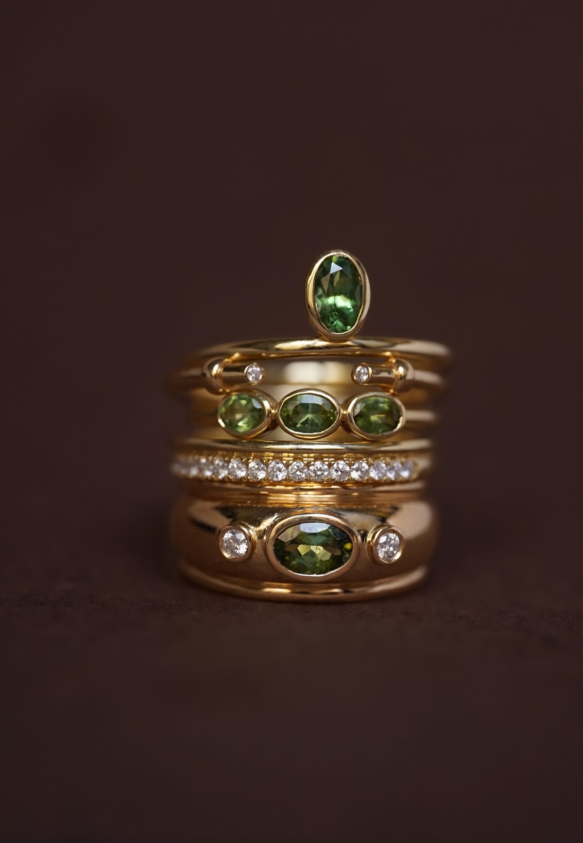 Stack en nature morte de la Bague Décentrée Verte Valentine, la Bague Ajourée Valentine, la Bague Trio Vert Valentine, l'Alliance Double Anneau Iris, la Bague Dôme Verte Valentine, en or recyclé 18 carats et pierres fines et précieuses naturelles